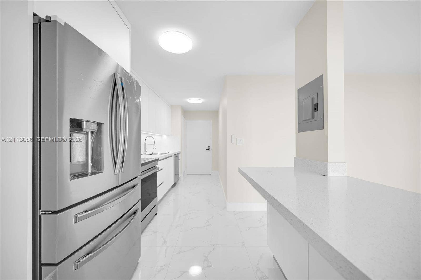 7135 Collins Avenue, #1632, Miami Beach, FL 33141 Kitchen featuring stainless steel refrigerator, white cabinetry, solid-surface countertops, and stone-finish tile flooring