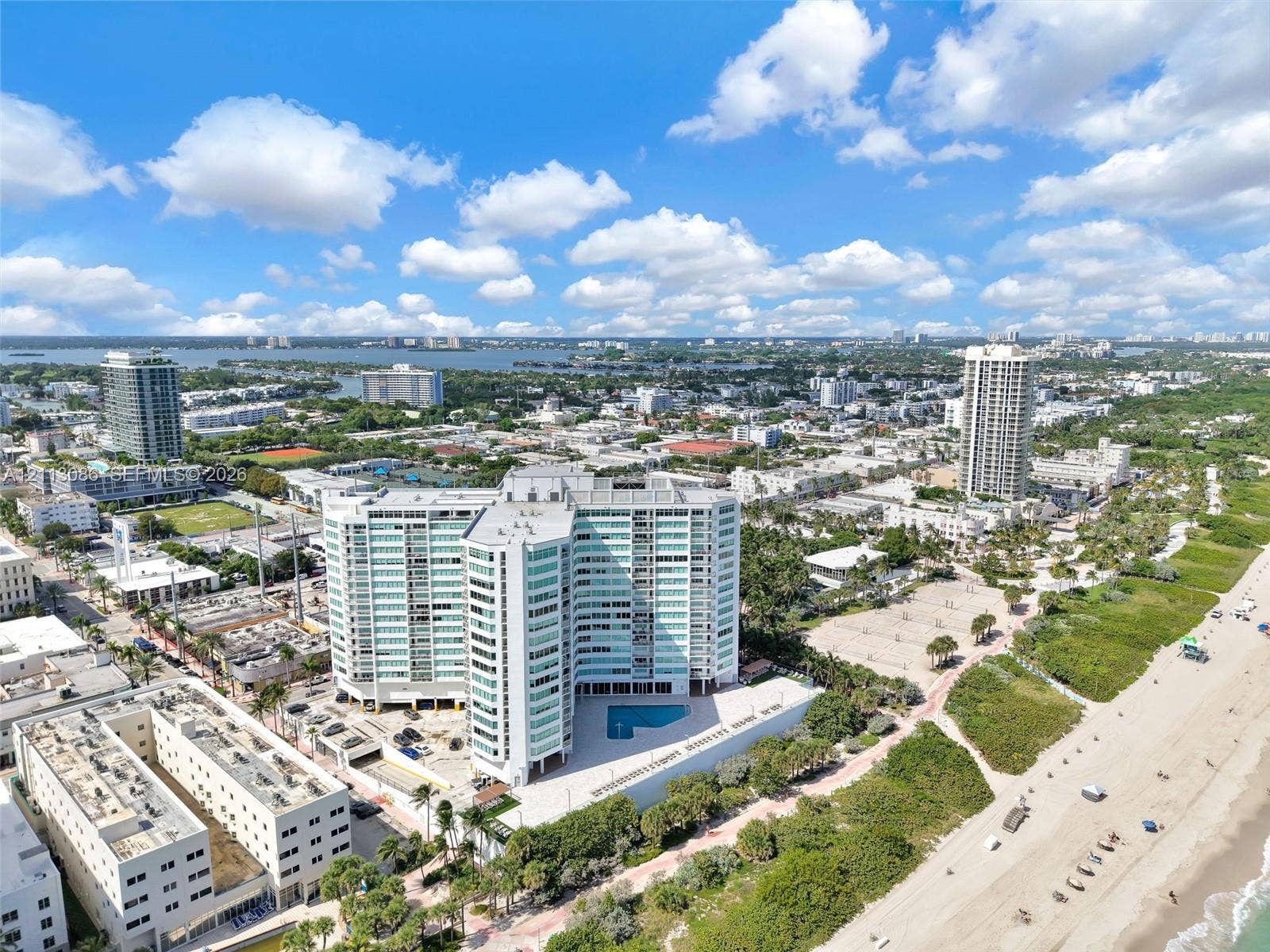 7135 Collins Avenue, #1632, Miami Beach, FL 33141 Aerial perspective of a high-rise residential building featuring floor-to-ceiling glass paneling, an outdoor swimming pool, and direct proximity to the coastline