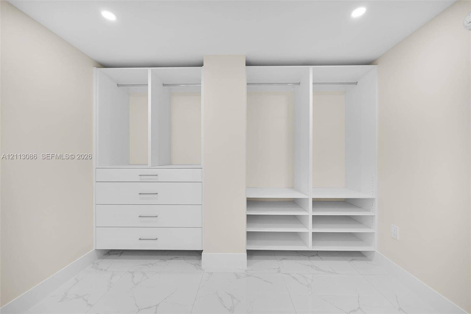 7135 Collins Avenue, #1632, Miami Beach, FL 33141 Custom white built-in cabinetry featuring hanging rods, four integrated storage drawers, and multiple open shelving units set against large-format, light-toned stone-finish flooring with prominent veining