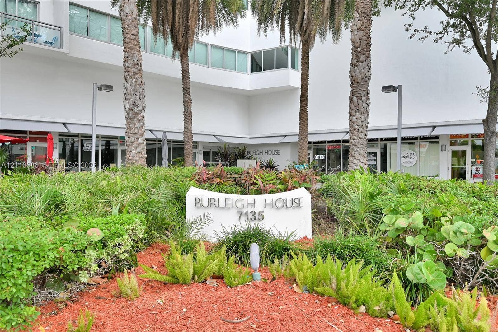 7135 Collins Avenue, #1632, Miami Beach, FL 33141 Exterior grounds featuring mature palm trees, tiered tropical landscaping, integrated signage, and architectural masonry