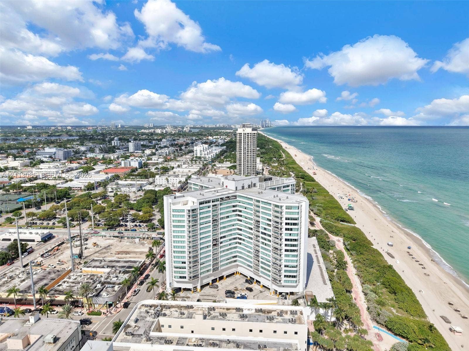 7135 Collins Avenue, #1632, Miami Beach, FL 33141 High-rise condominium building featuring a multi-wing architectural design, expansive glass balcony systems, covered ground-level parking, and immediate proximity to the Atlantic coastline