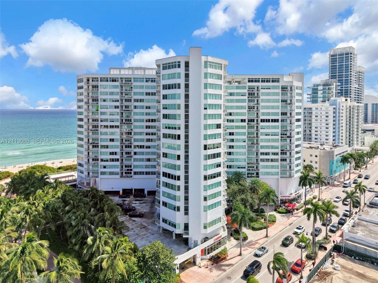 7135 Collins Avenue, #1632, Miami Beach, FL 33141 High-rise residential building featuring a glass-paneled facade, private balconies, covered parking, and proximity to the oceanfront