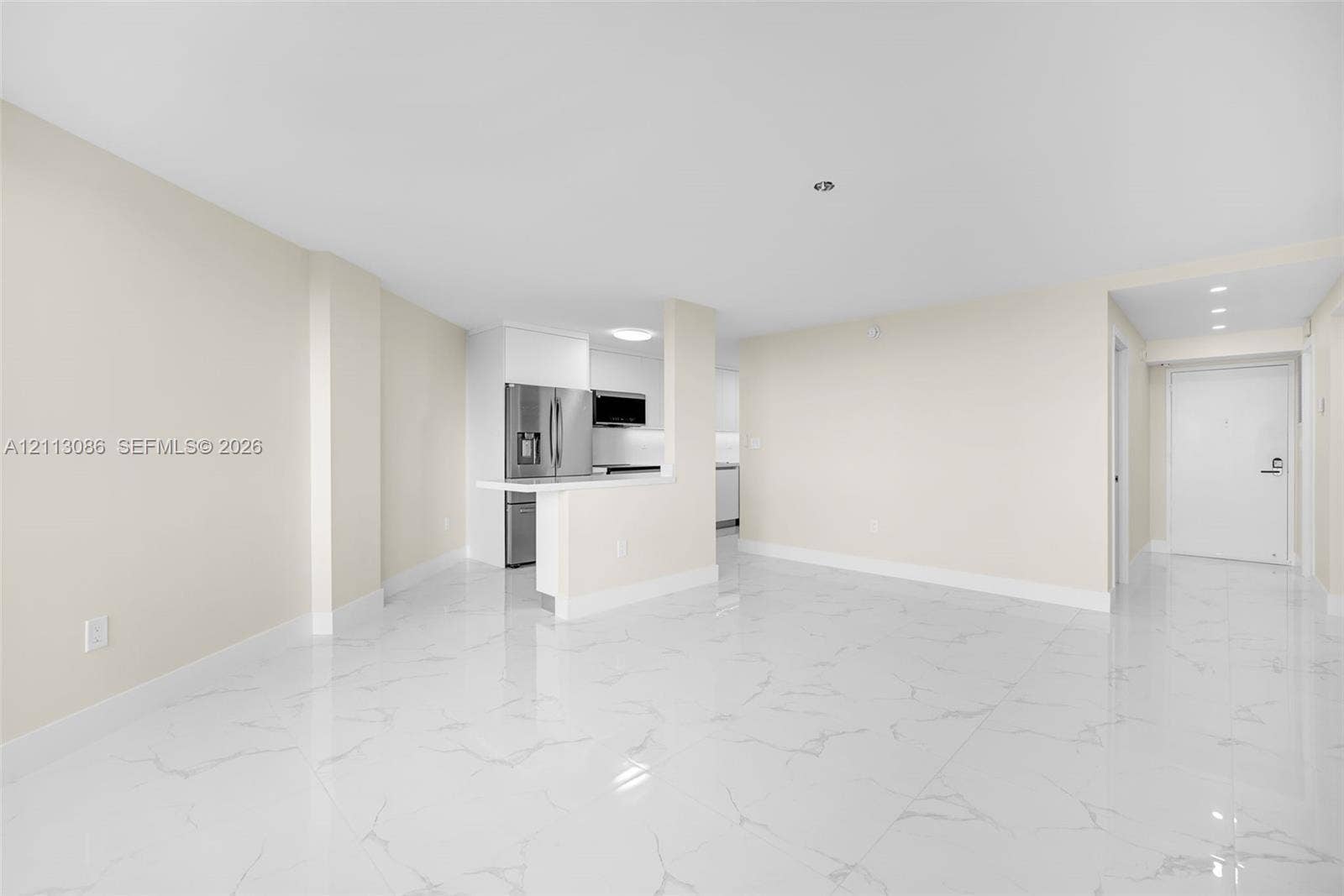 7135 Collins Avenue, #1632, Miami Beach, FL 33141 Open-concept interior featuring large-format tile flooring with a veined pattern, a breakfast bar with a solid surface countertop, stainless steel kitchen appliances, and recessed ceiling lighting