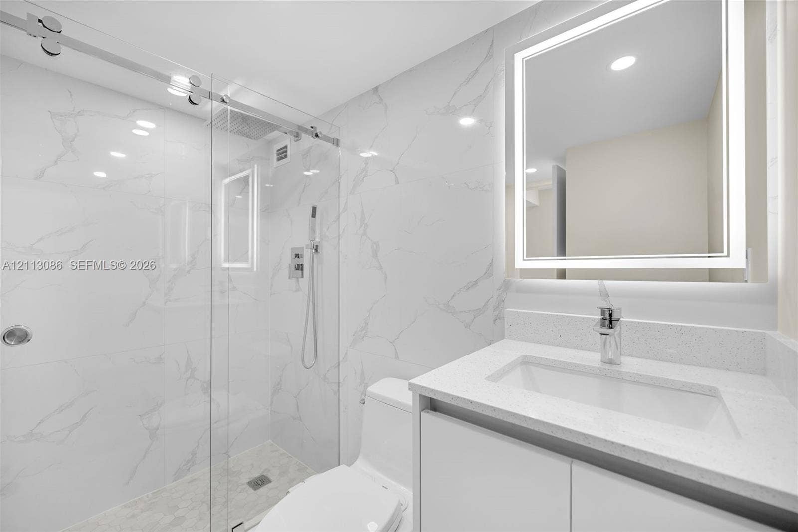 7135 Collins Avenue, #1632, Miami Beach, FL 33141 Bathroom featuring a glass-enclosed walk-in shower with stone-finish wall tile, a stone-composite countertop, a vessel-style sink, and a wall-mounted LED mirror