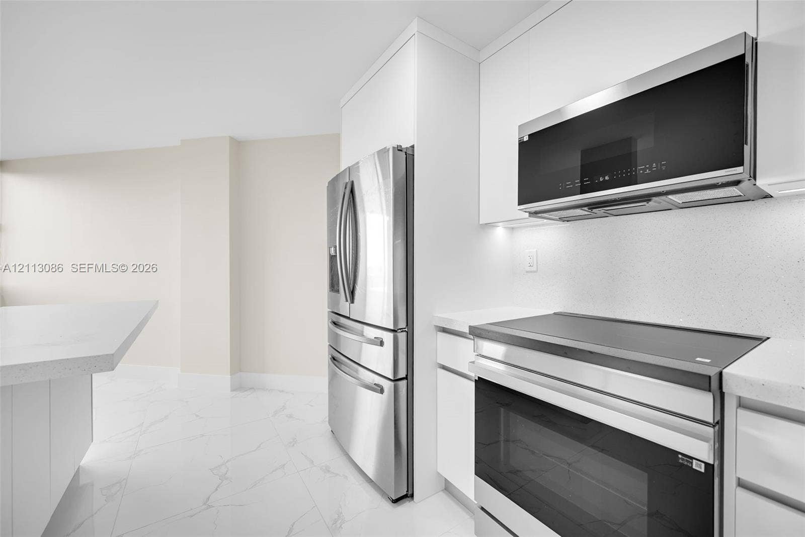 7135 Collins Avenue, #1632, Miami Beach, FL 33141 Kitchen featuring white flat-panel cabinetry, light-toned stone-surface countertops, stainless steel appliances, and large-format porcelain tile flooring