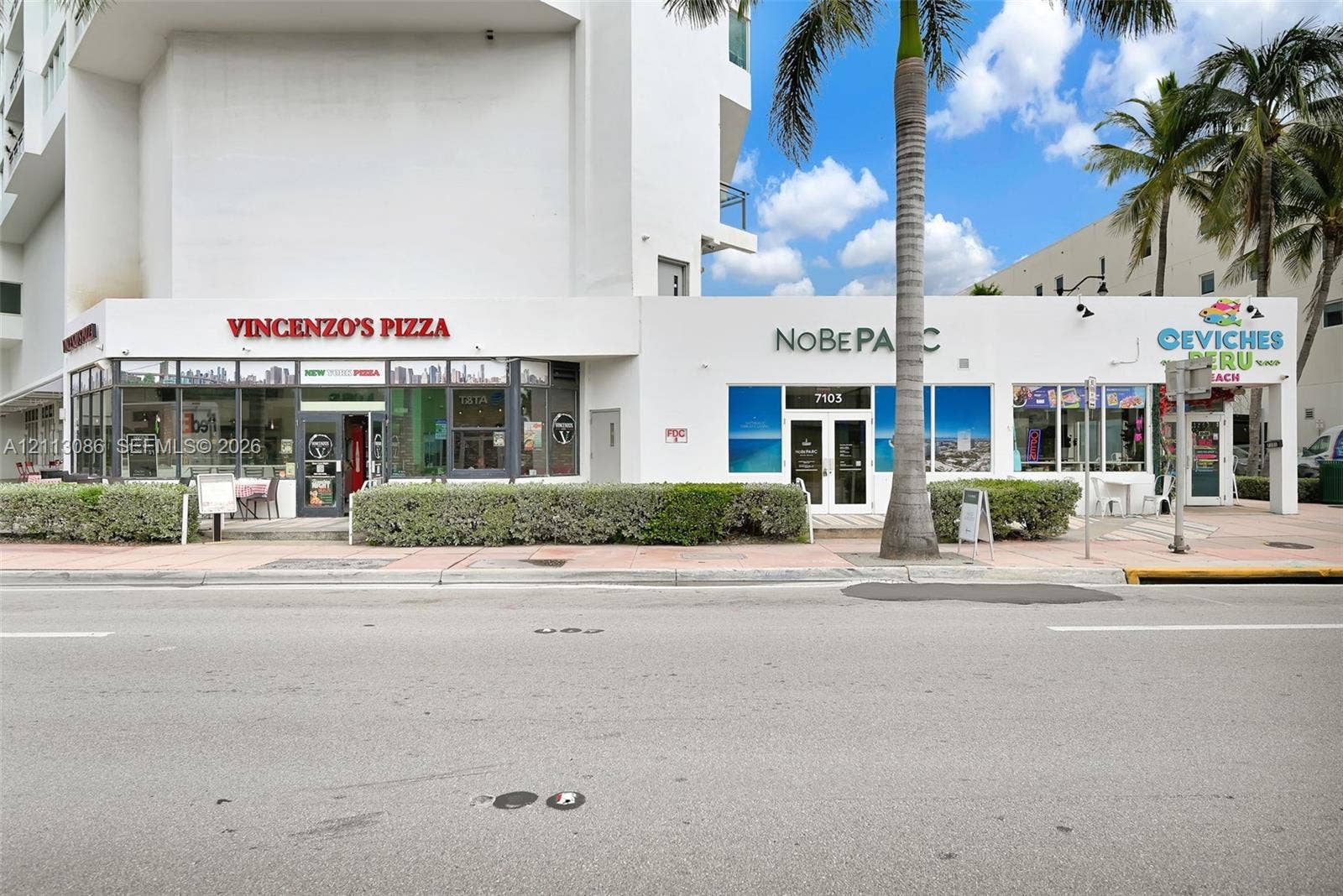 7135 Collins Avenue, #1632, Miami Beach, FL 33141 Street-level commercial storefronts featuring expansive glass windows, paved sidewalk access, and integrated landscaping