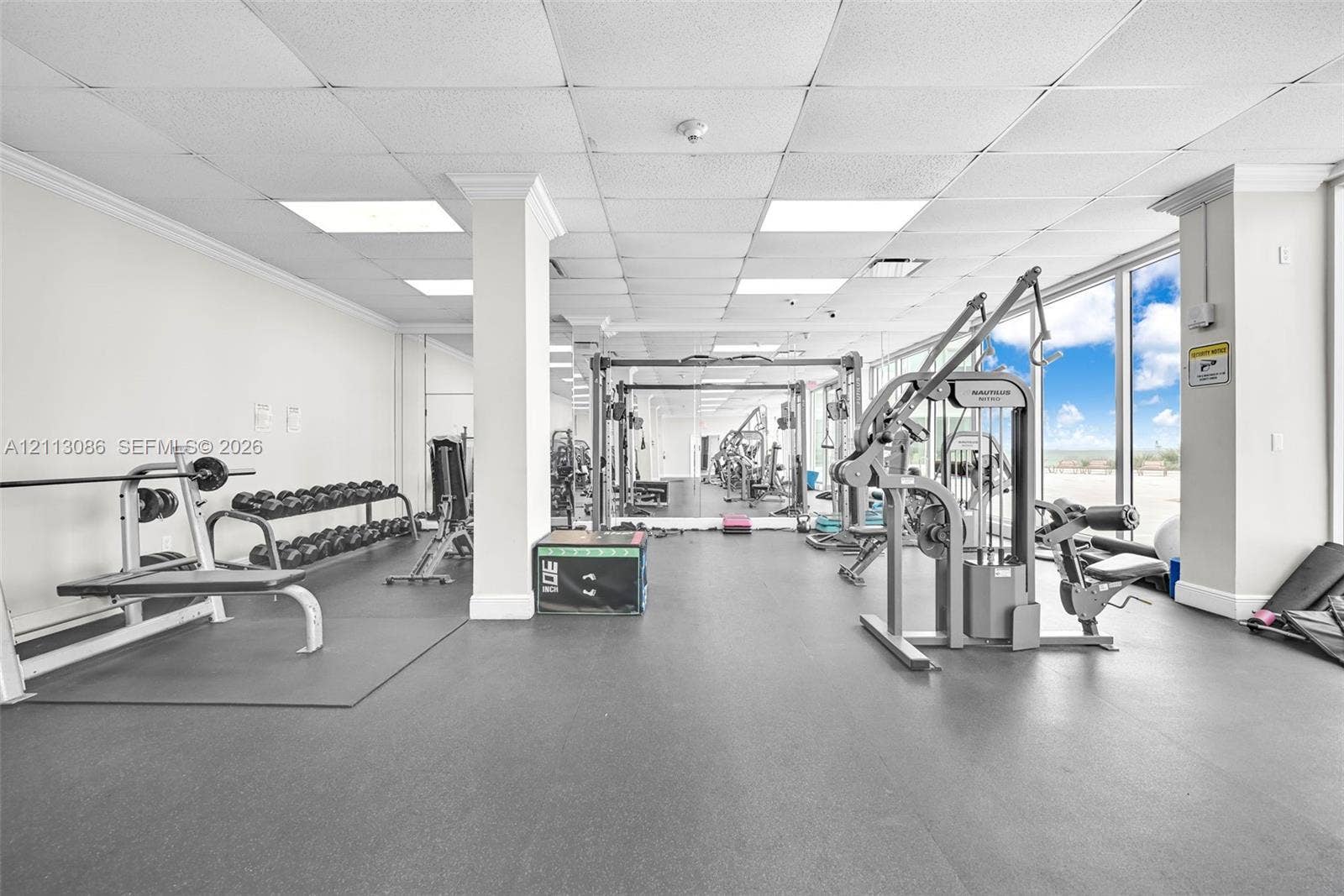 7135 Collins Avenue, #1632, Miami Beach, FL 33141 Fitness center featuring rubber flooring, ceiling-mounted recessed lighting, and wall-to-wall mirrored surfaces with floor-to-ceiling glass windows