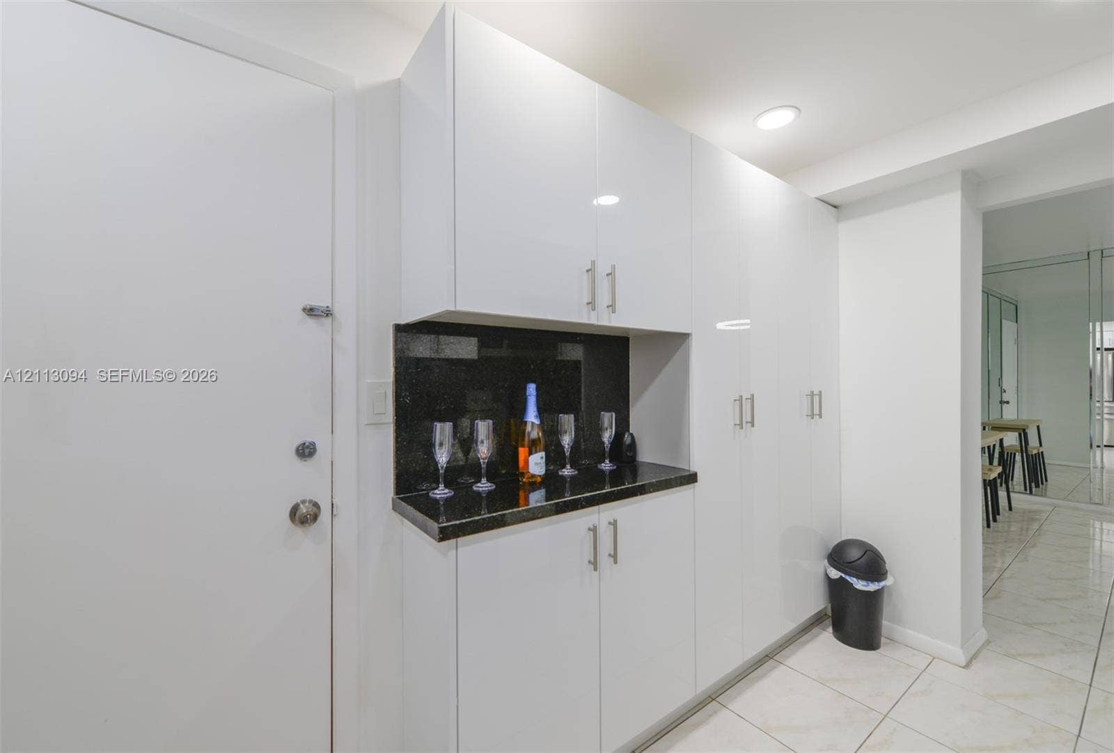 Built-in white cabinetry with high-gloss finish, contrasting dark stone countertop, and recessed ceiling lighting