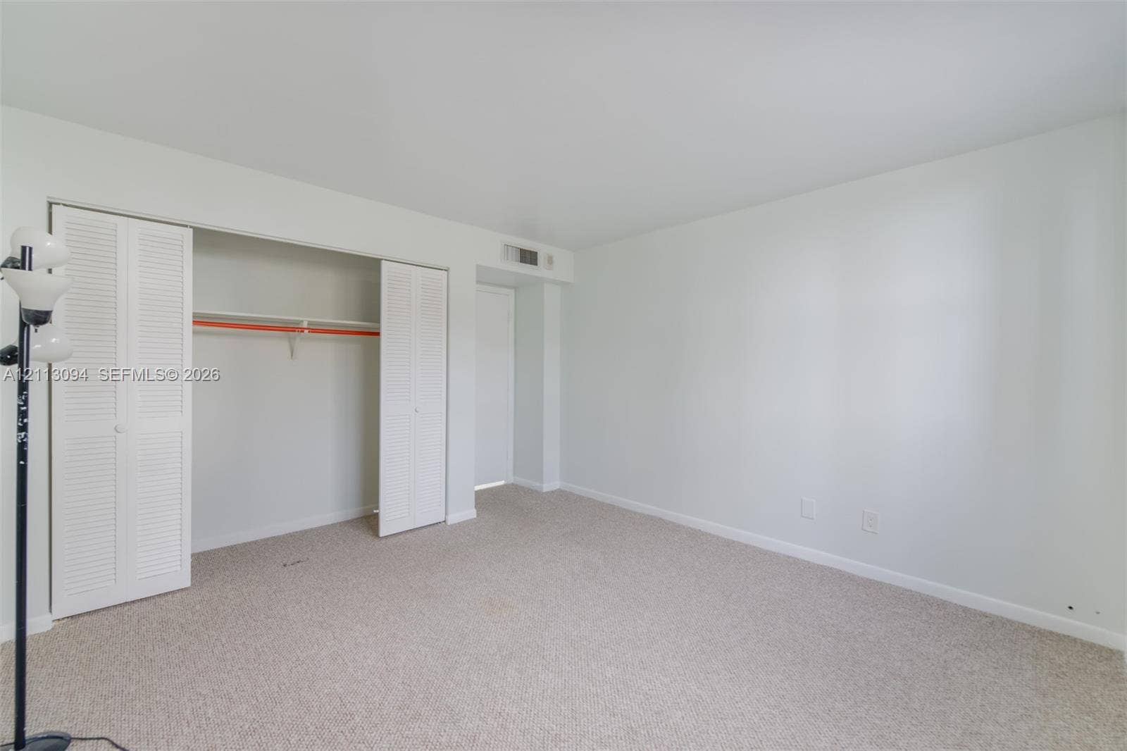 Neutral-toned interior featuring wall-to-wall carpeting, white walls, and a closet with bifold louvered doors