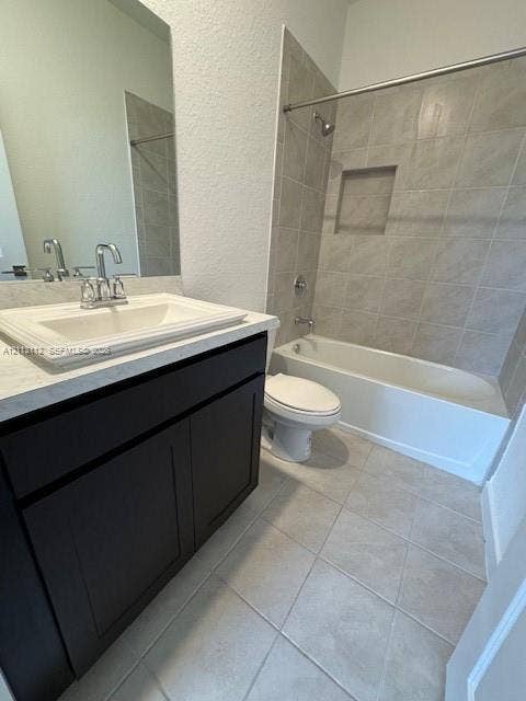 557 NE 5th Terrace, Florida City, Florida City, FL 33034 Bathroom featuring a dark wood-finish vanity, light stone-composite countertop with integrated sink, porcelain tile flooring, and a tiled tub-shower combination with a built-in recessed niche