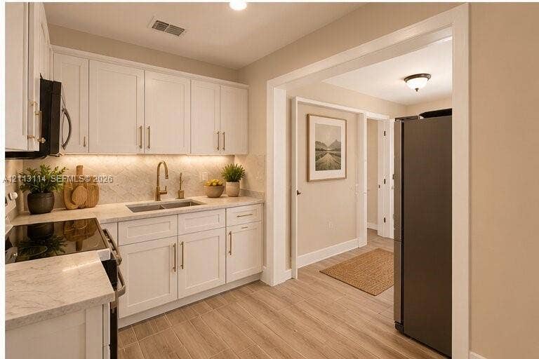 AI-generated photo of the kitchen featuring white shaker-style cabinetry, stone-patterned countertops, a patterned tile backsplash, under-cabinet lighting, and wood-finish flooring
