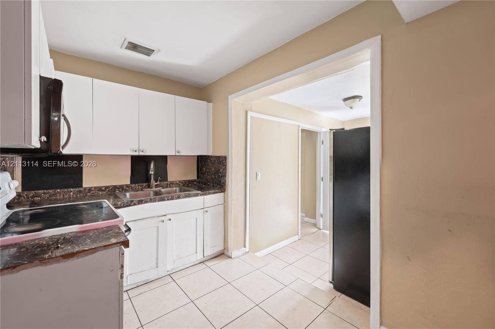 Kitchen featuring white cabinetry, stone-finish countertops, tile flooring, and a double-basin stainless steel sink