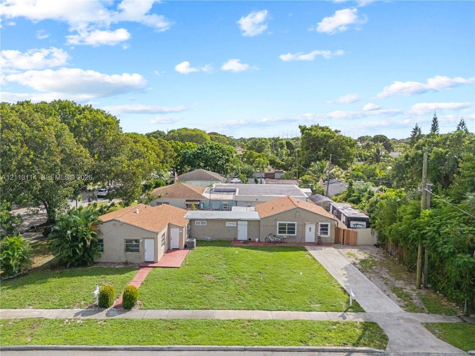 Single-story residence featuring a shingled roof, neutral exterior finish, concrete driveway, and expansive lawn area