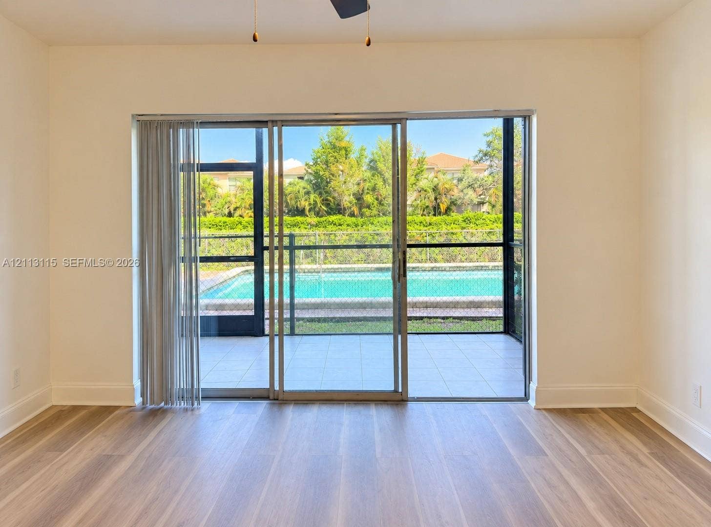 8705 NW 38th Drive, #4A, Coral Springs, Coral Springs, FL 33065 Wood-finish flooring, large sliding glass doors, and a screened-in patio featuring an in-ground swimming pool