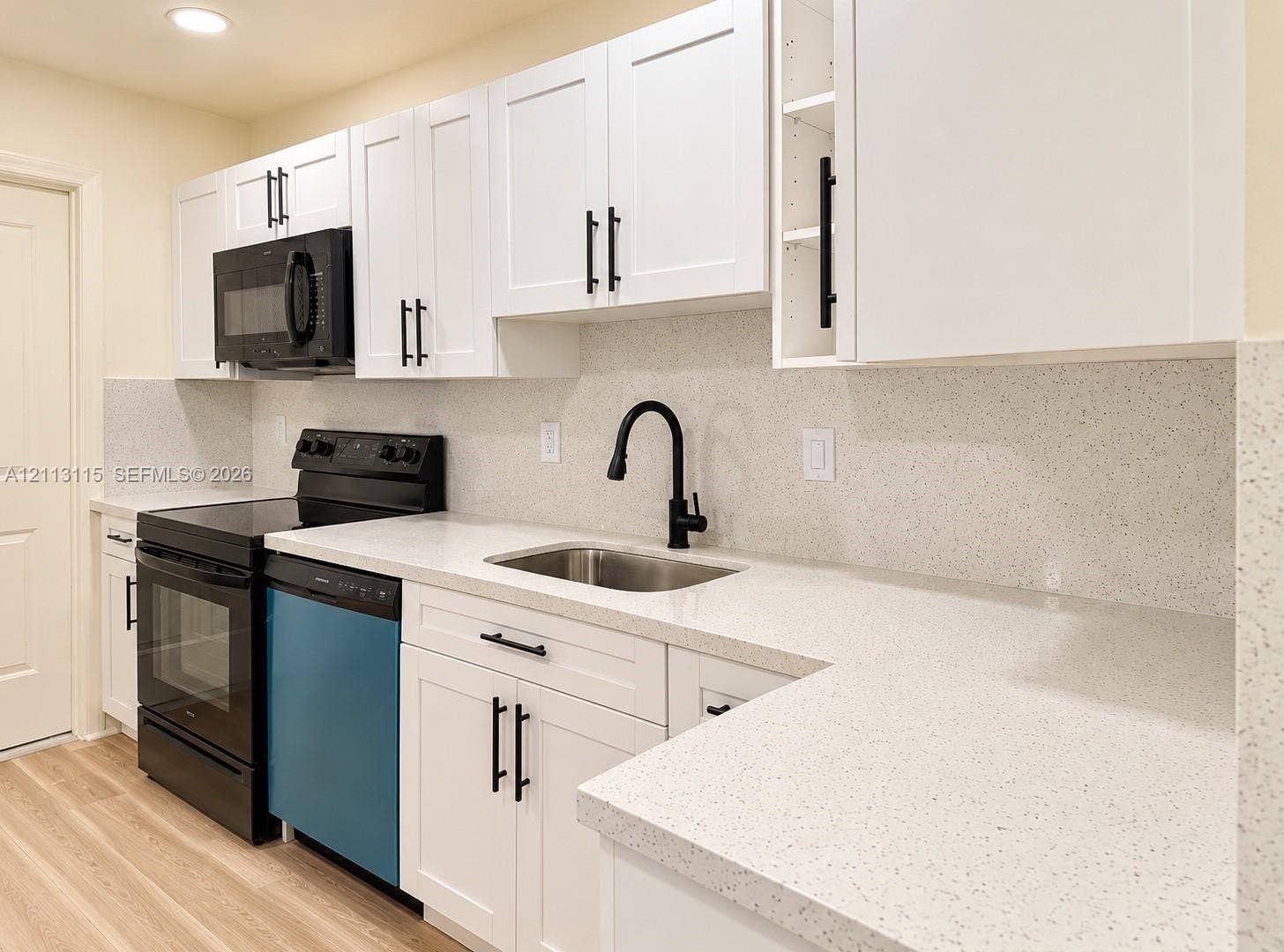 8705 NW 38th Drive, #4A, Coral Springs, Coral Springs, FL 33065 Kitchen featuring shaker-style white cabinetry, light-toned composite countertops, a stainless steel undermount sink with a matte black high-arch faucet, and black appliance package