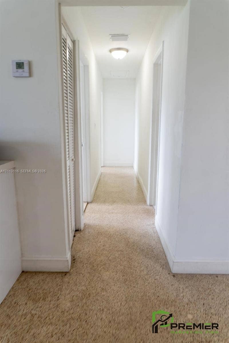 4341 NW 178th Drive, Miami Gardens, FL 33055 Hallway featuring neutral-toned carpeting, louvered closet doors, and a ceiling-mounted flush mount light fixture