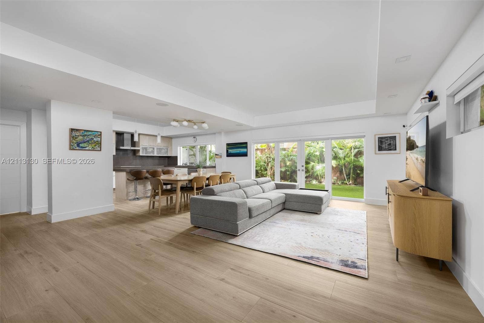 Open-concept interior featuring recessed lighting, wood-finish flooring, a tray ceiling, and glass sliding doors leading to a private outdoor space