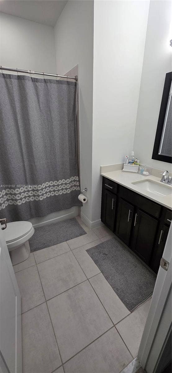 16474 Sea Turtle Place, Westlake, Westlake, FL 33470 Bathroom featuring dark wood-finish cabinetry, a light-toned solid surface countertop, rectangular under-mount sink, tiled flooring, and a shower-tub combination