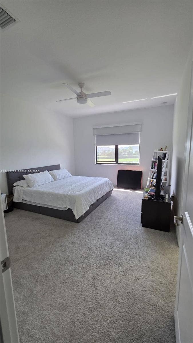 16474 Sea Turtle Place, Westlake, Westlake, FL 33470 Neutral-toned wall-to-wall carpeting, ceiling fan with integrated lighting, and single-pane window with a roller shade