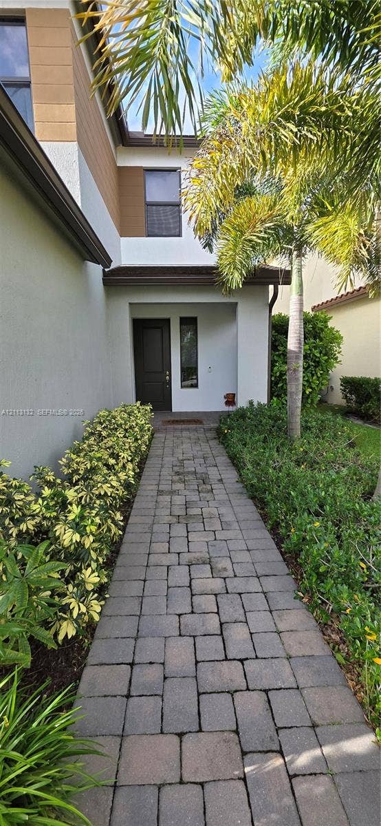 16474 Sea Turtle Place, Westlake, Westlake, FL 33470 Paver walkway leading to a recessed entryway with a solid wood-finish door and exterior stucco facade