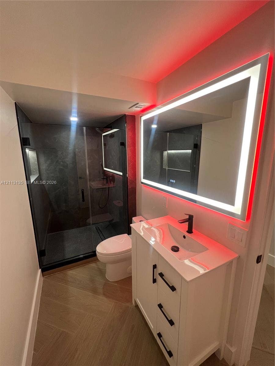1600 S Ocean Drive, #3A, Hollywood, FL 33019 White vanity with matte black hardware, integrated sink, and stone-finish countertop paired with a rectangular LED-backlit mirror