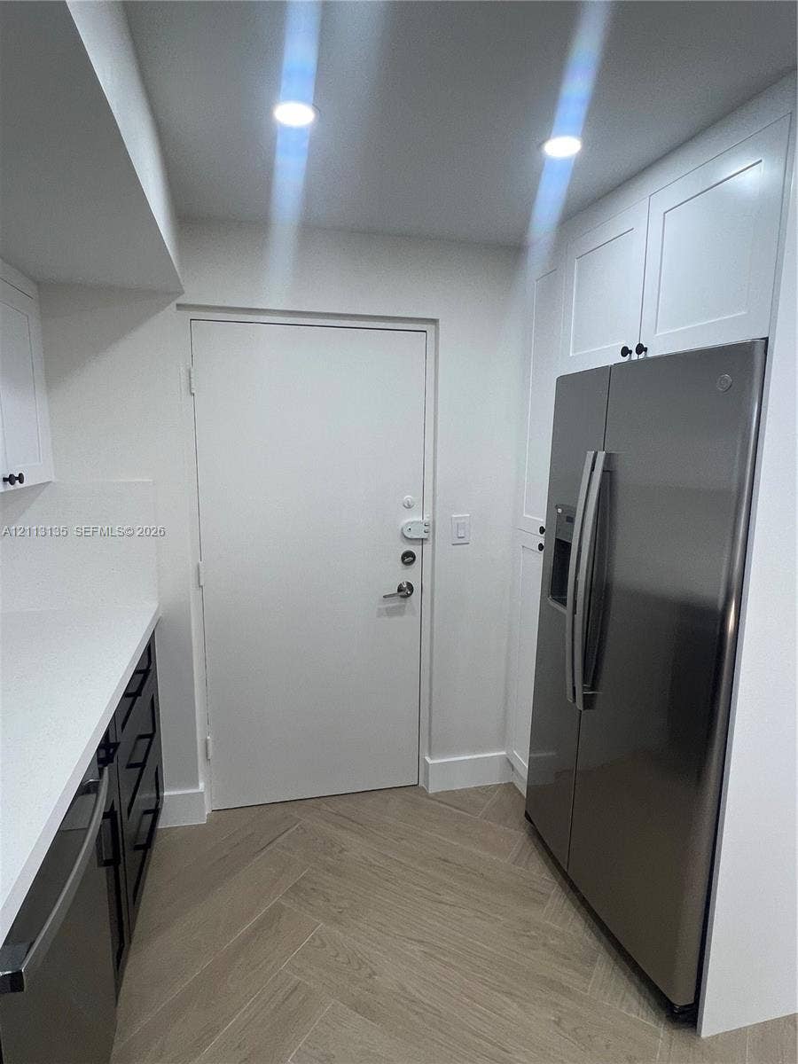 1600 S Ocean Drive, #3A, Hollywood, FL 33019 Shaker-style white cabinetry, stainless steel side-by-side refrigerator, solid-surface countertops, recessed lighting, and herringbone-patterned flooring
