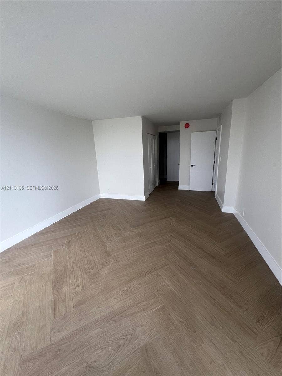 1600 S Ocean Drive, #3A, Hollywood, FL 33019 Neutral-toned interior space featuring herringbone-pattern wood-finish flooring and solid core swing doors