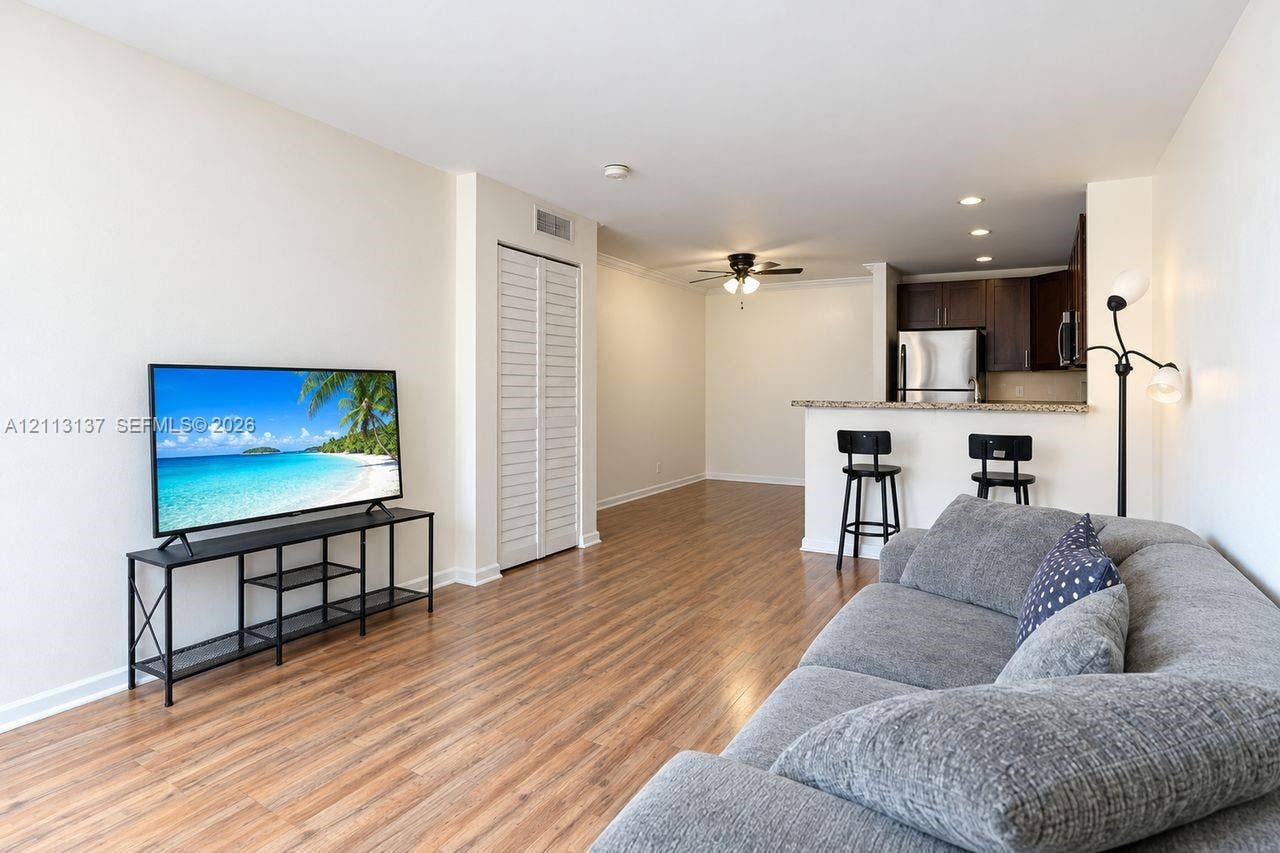 10884 Royal Palm Boulevard, #10884, Coral Springs, FL 33065 Wood-finish flooring, breakfast bar with stone-finish countertop, stainless steel appliances, dark wood-finish cabinetry, and louvered closet doors