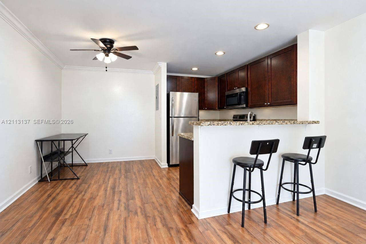 10884 Royal Palm Boulevard, #10884, Coral Springs, FL 33065 Kitchen featuring dark wood cabinetry, stone-surface breakfast bar, recessed lighting, ceiling fan, and wood-finish flooring