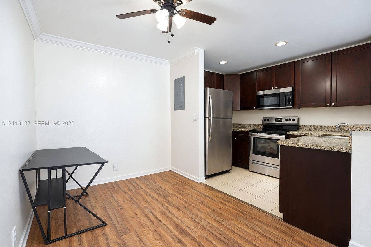 10884 Royal Palm Boulevard, #10884, Coral Springs, FL 33065 Kitchen featuring dark wood cabinetry, stone-finish countertops, stainless steel appliances, tile flooring, and wood-finish flooring