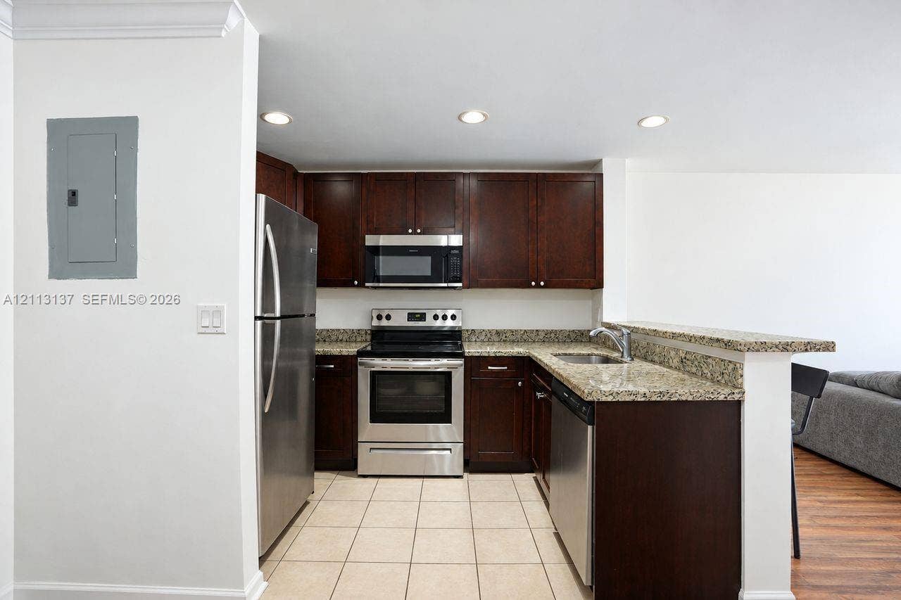 10884 Royal Palm Boulevard, #10884, Coral Springs, FL 33065 Kitchen featuring dark wood cabinetry, stone countertops, stainless steel appliances, and tiled flooring