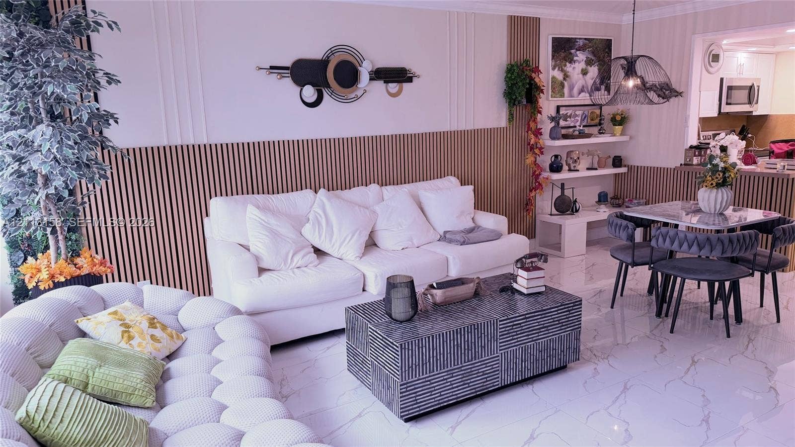 Living area featuring vertical slat wood wall paneling, polished stone-finish flooring with vein detailing, built-in shelving, and a decorative pendant light fixture