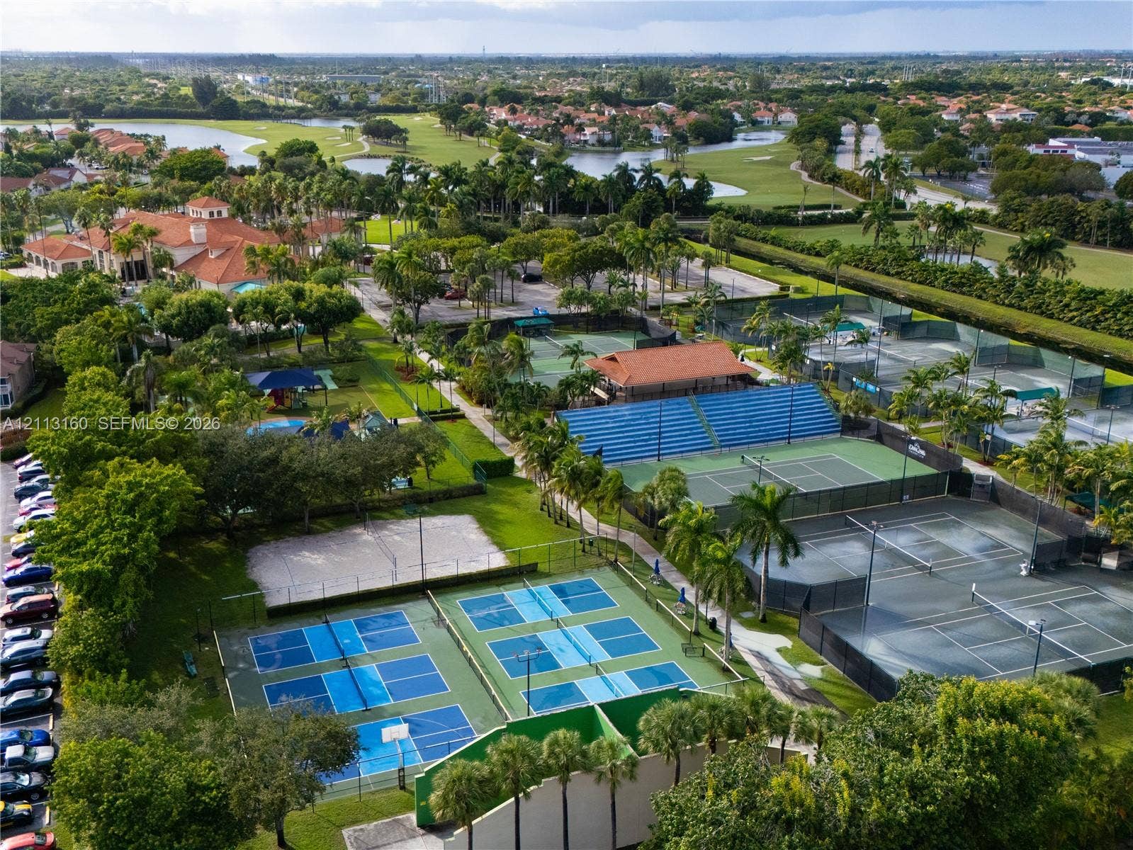 Recreational complex featuring multiple tennis courts, pickleball courts, bleacher seating, and landscaped grounds
