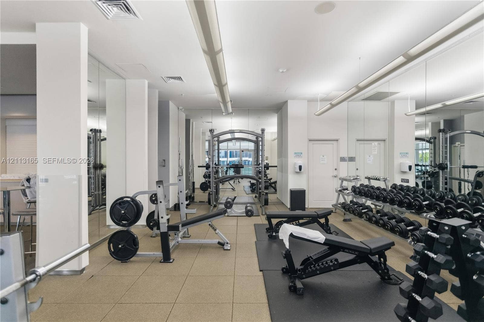 10275 Collins Avenue, #229, Bal Harbour, FL 33154 Fitness facility featuring industrial-style suspended lighting, full-length wall mirrors, and textured tile flooring