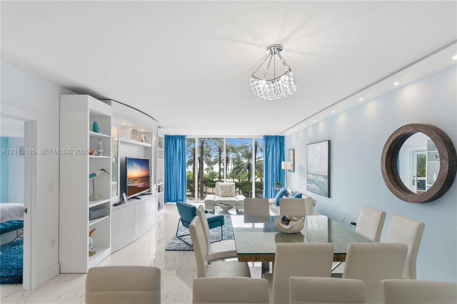10275 Collins Avenue, #229, Bal Harbour, FL 33154 Open-concept living space featuring white polished stone flooring, custom floor-to-ceiling built-in cabinetry, recessed and statement crystal pendant lighting, and floor-to-ceiling glass windows