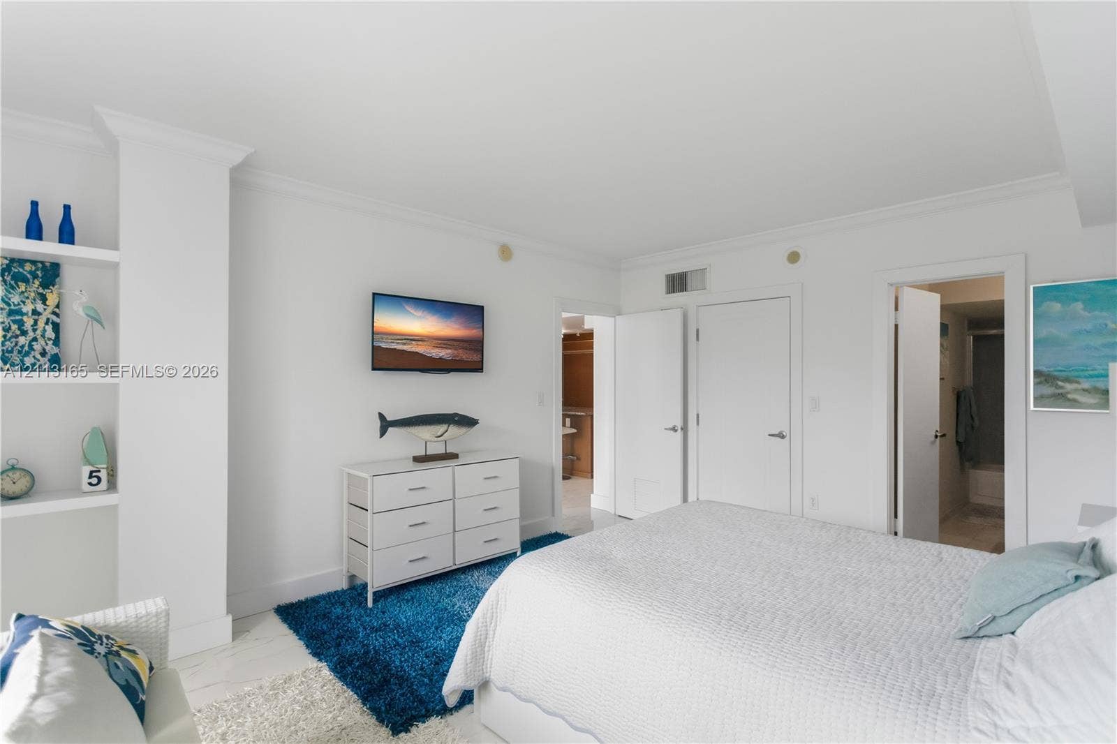 10275 Collins Avenue, #229, Bal Harbour, FL 33154 Room featuring crisp white walls, built-in shelving, crown molding, and neutral flooring