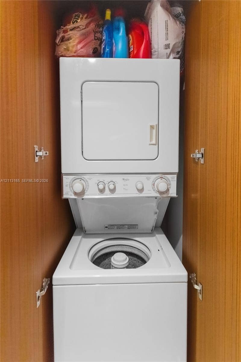 10275 Collins Avenue, #229, Bal Harbour, FL 33154 Stacked laundry unit enclosed within built-in cabinetry featuring wood-finish paneling and interior metal hinges