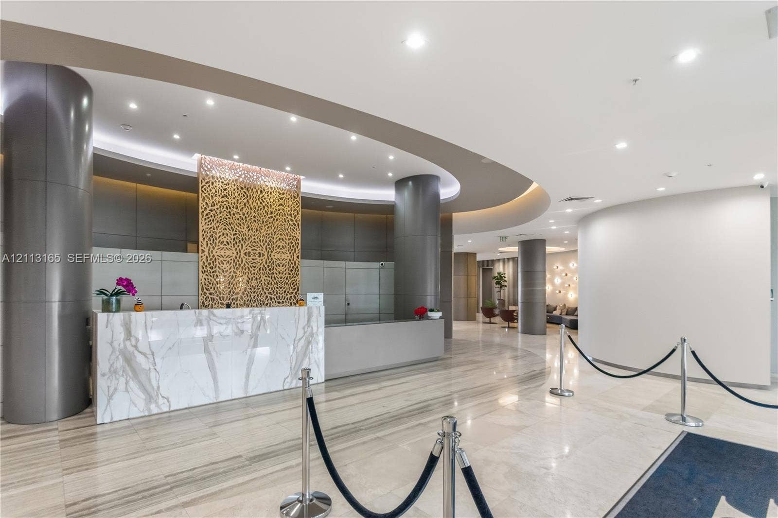 10275 Collins Avenue, #229, Bal Harbour, FL 33154 Grand lobby featuring stone-surfaced reception desk, recessed ceiling lighting, decorative metal lattice wall paneling, and polished stone flooring