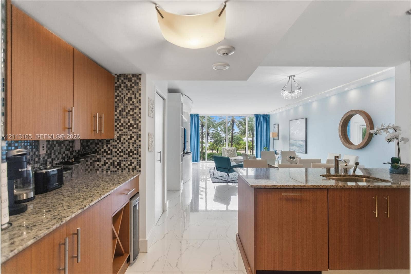 10275 Collins Avenue, #229, Bal Harbour, FL 33154 Kitchen featuring flat-panel wood cabinetry, stone countertops, integrated wine storage, mosaic tile backsplash, and stone-finish flooring