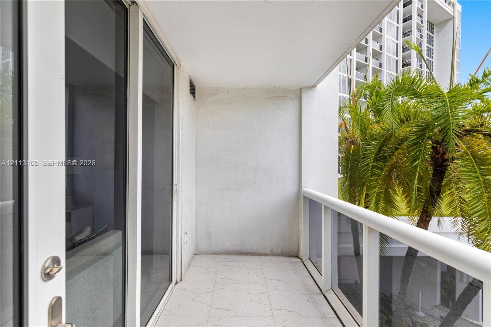10275 Collins Avenue, #229, Bal Harbour, FL 33154 Covered balcony featuring tile flooring, glass panel railings, and floor-to-ceiling sliding glass doors