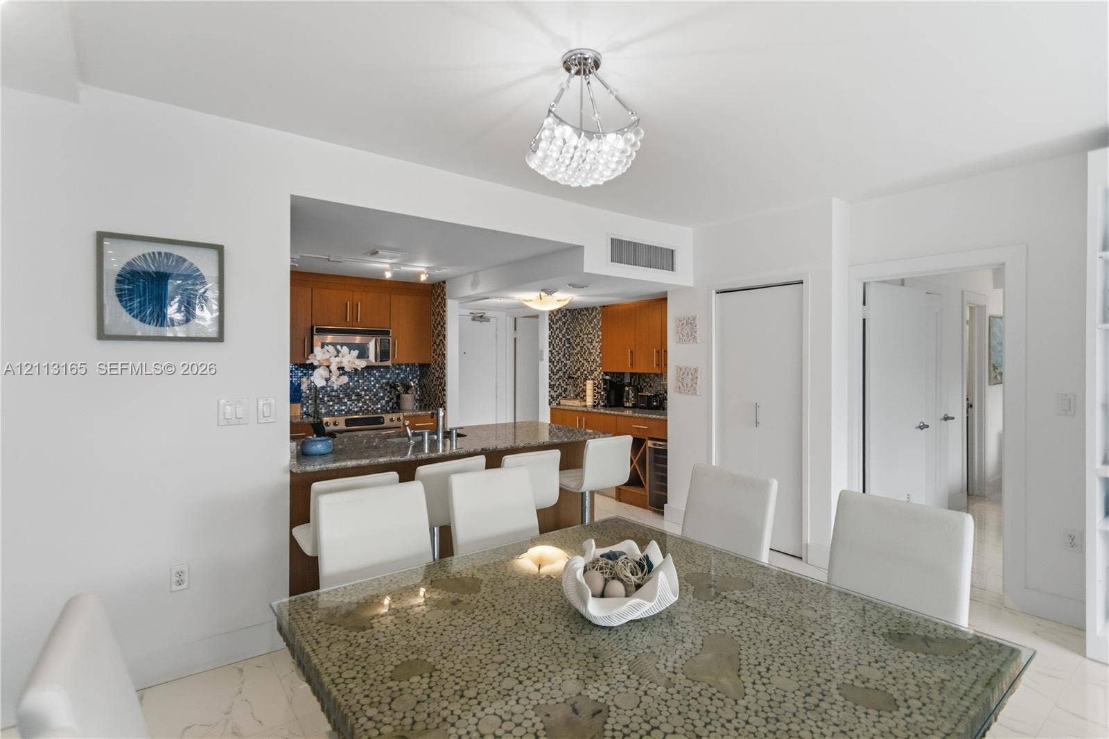 10275 Collins Avenue, #229, Bal Harbour, FL 33154 Open-concept kitchen featuring wood cabinetry, stone countertops, a breakfast bar, and decorative tile backsplash
