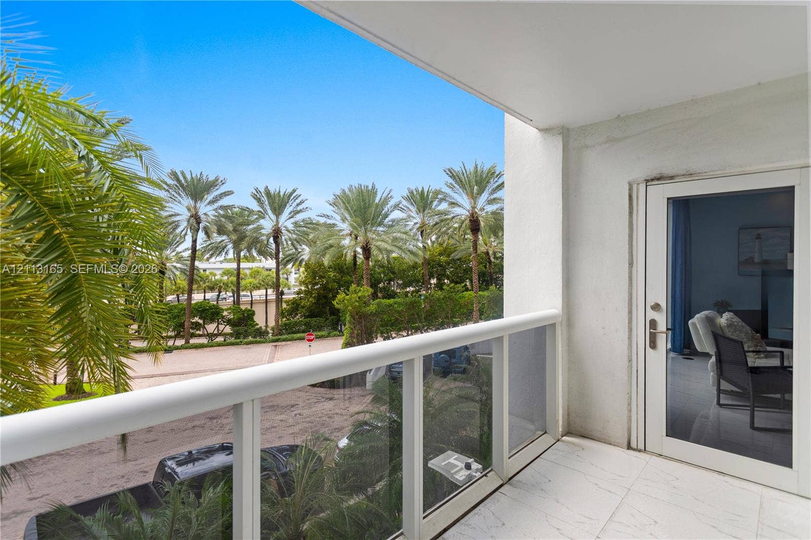 10275 Collins Avenue, #229, Bal Harbour, FL 33154 Covered balcony featuring white tiled flooring, a glass panel railing, and a full-height glass door entry