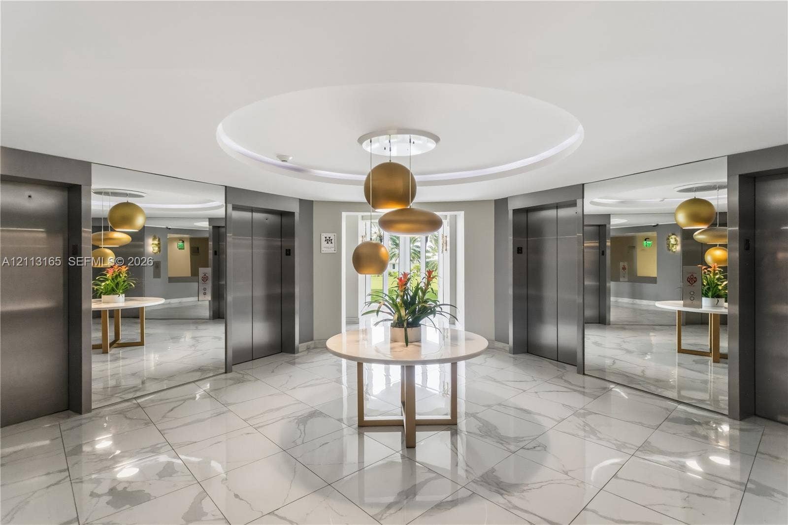 10275 Collins Avenue, #229, Bal Harbour, FL 33154 Elevator lobby featuring polished stone flooring, recessed circular ceiling detail, stainless steel elevator doors, full-height wall mirrors, and tiered metallic pendant lighting