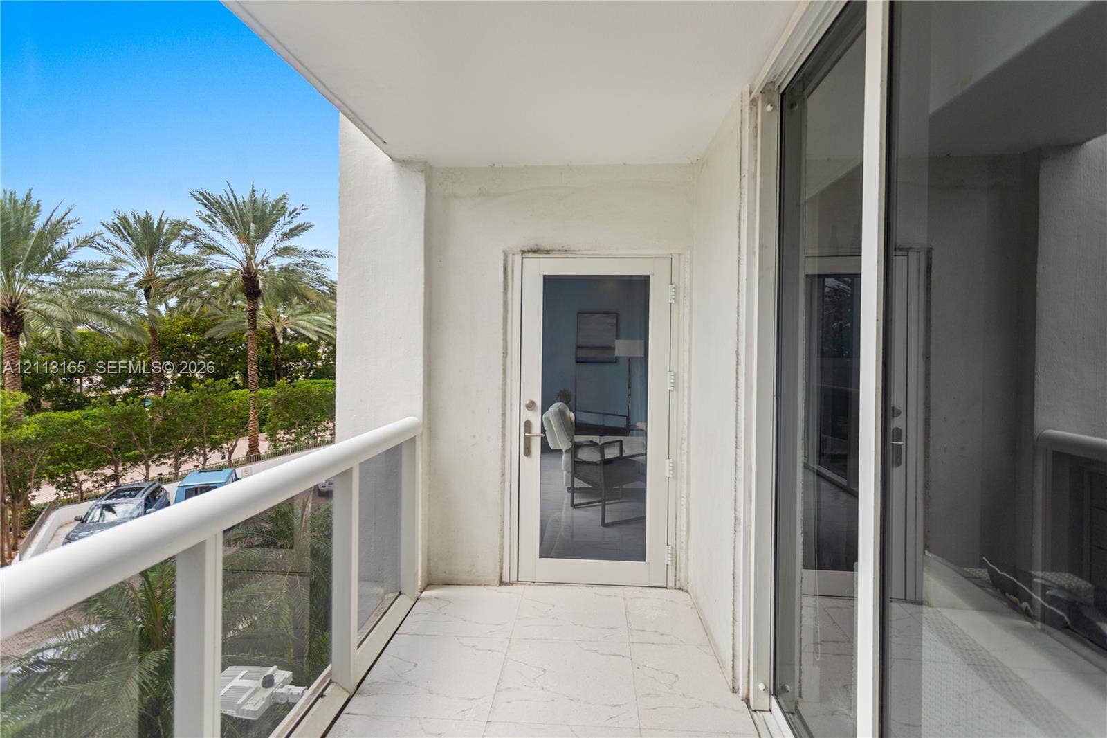 10275 Collins Avenue, #229, Bal Harbour, FL 33154 Covered balcony featuring white tiled flooring, a glass-panel railing, and a full-height glass entry door