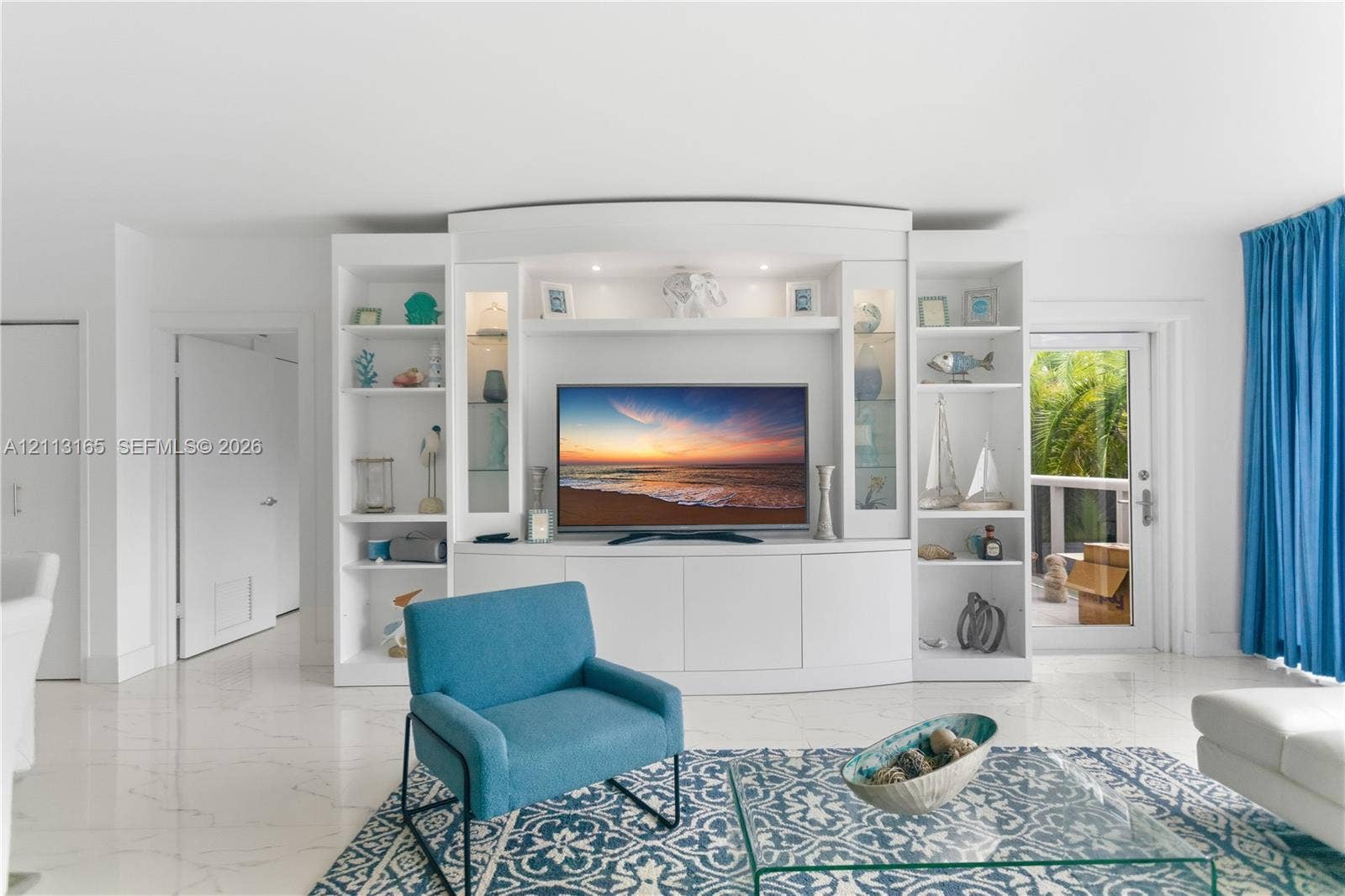 10275 Collins Avenue, #229, Bal Harbour, FL 33154 Custom built-in white shelving unit featuring glass-front cabinets, recessed display lighting, and lower storage cabinetry