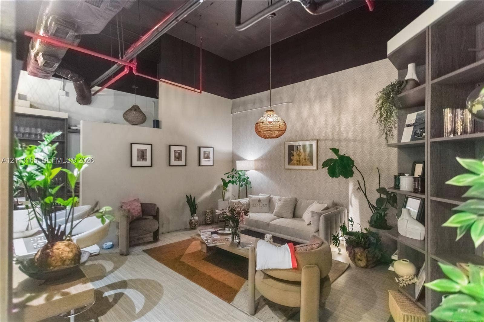 10275 Collins Avenue, #229, Bal Harbour, FL 33154 Industrial-style exposed ceiling with red fire suppression piping, high ceilings, custom built-in dark wood shelving unit, and patterned wallpaper accent wall