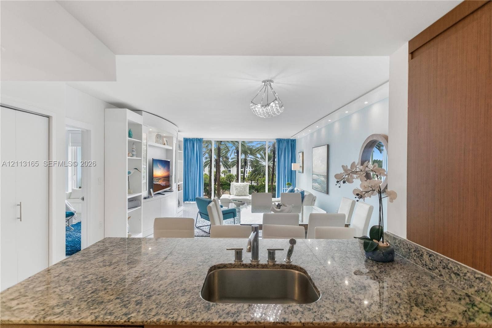 10275 Collins Avenue, #229, Bal Harbour, FL 33154 Stone countertop featuring an integrated stainless steel under-mount sink with a pull-down sprayer faucet, custom built-in cabinetry, floor-to-ceiling windows, and a crystal chandelier