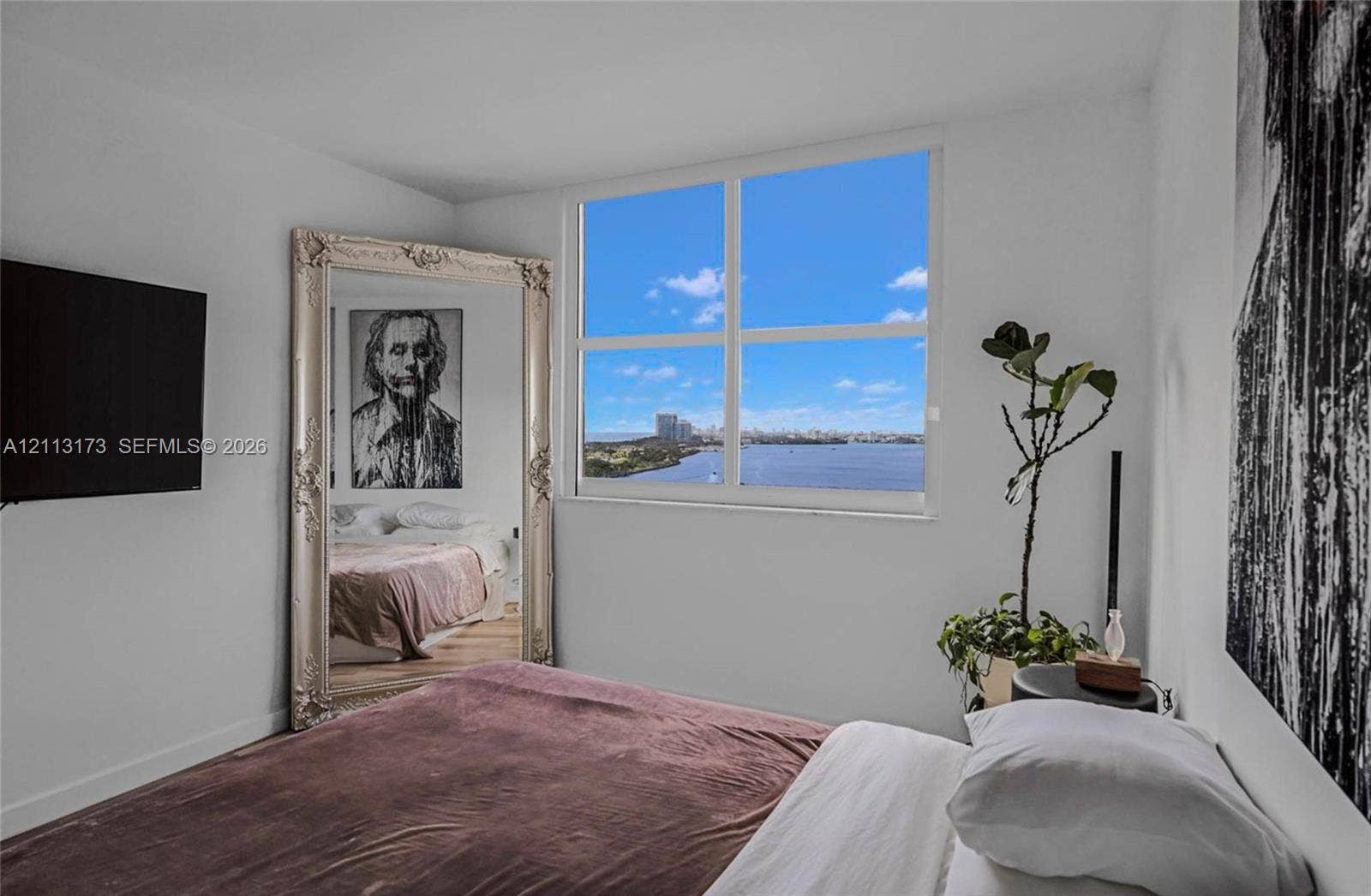 300 Bayview Drive, #1614, Sunny Isles Beach, FL 33160 Large rectangular window featuring water and city skyline scenery, neutral wall finishes, and wood-finish flooring