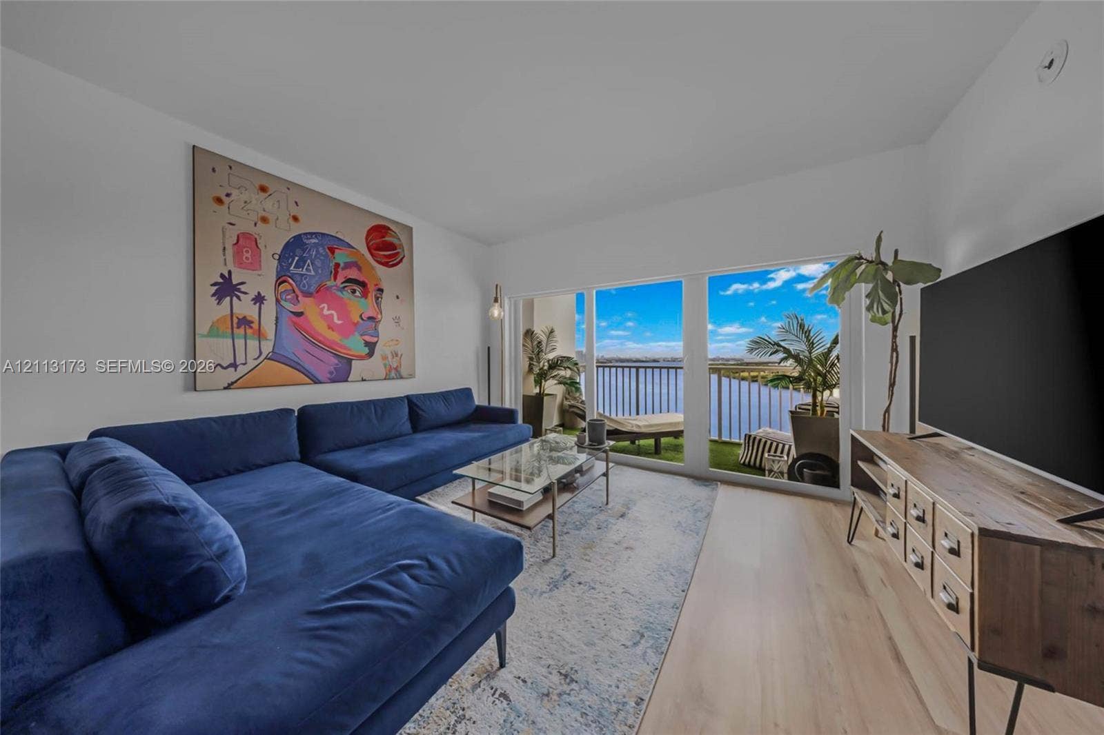 300 Bayview Drive, #1614, Sunny Isles Beach, FL 33160 Living area featuring light-toned wood-finish flooring, full-height sliding glass doors, and a private balcony with metal railing