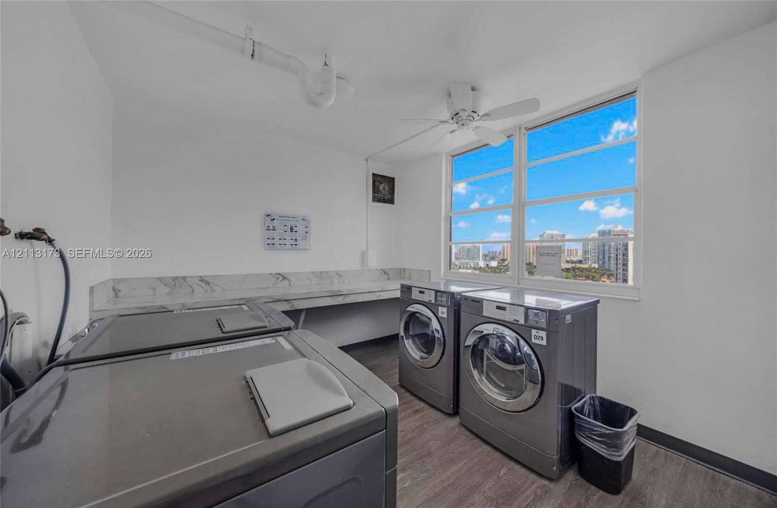 300 Bayview Drive, #1614, Sunny Isles Beach, FL 33160 Laundry area featuring wood-finish flooring, a stone-patterned backsplash, large windows, and an attached ceiling fan